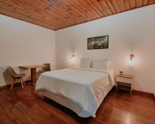 1 dormitorio con cama blanca y techo de madera en Casa Wald, en Campos do Jordão