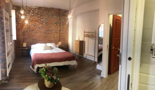 a bedroom with a bed and a brick wall at Hostal Albany Ancha in León