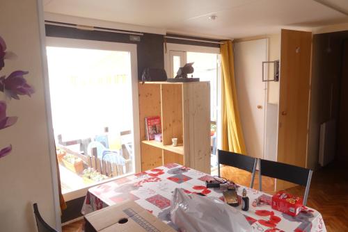 uma sala de jantar com uma mesa e uma janela em mobil-hom mag em Saillagouse