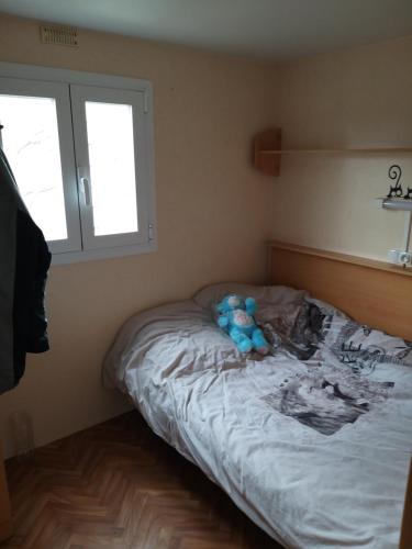 Un dormitorio con una cama con un osito de peluche. en mobil-hom mag, en Saillagouse