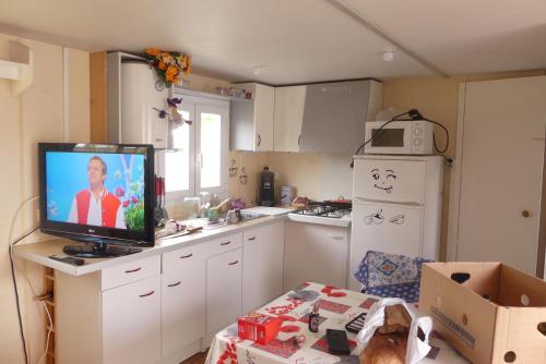 une cuisine avec une télévision à écran plat sur un comptoir dans l'établissement mobil-hom mag, à Saillagouse