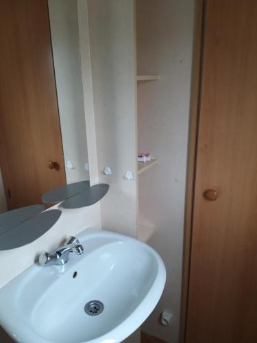 uma casa de banho com um lavatório branco e um espelho. em mobil-hom mag em Saillagouse