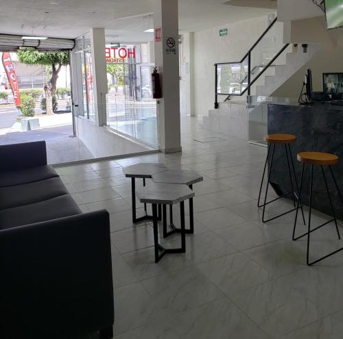 a lobby with tables and stools in a store at Hotel Estadía in León