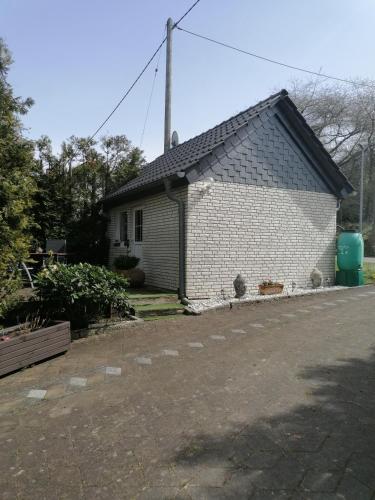 uma pequena casa de tijolos brancos com telhado em 25qm großes Ferienhäuschen " Der Hengstall" auf unserem Reiterhof em Birkenbeul