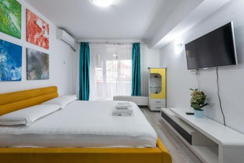 a white bedroom with a large bed and a flat screen tv at Bucharest Old Town Apartments in Bucharest