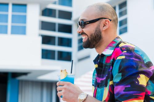 a man in a tie dye shirt holding a drink at Clevelander Hotel in Miami Beach