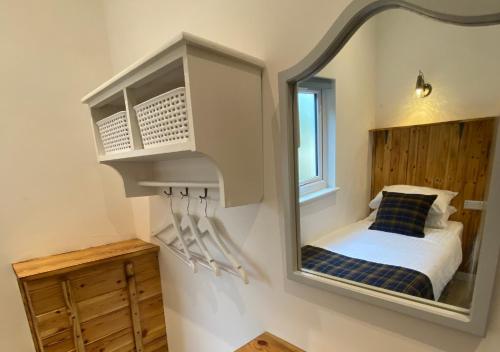 a mirror on a wall with a bed in a room at Minimoore Lodge. Perfect for walkers, cyclists and surfers. in Scorrier