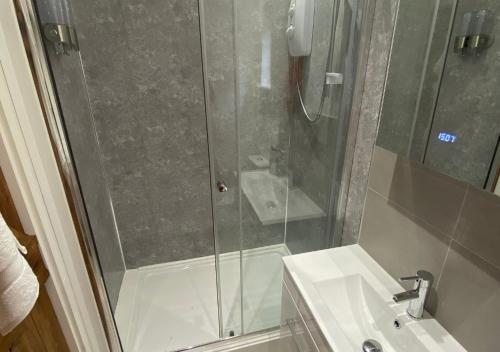 a shower with a glass door next to a sink at Minimoore Lodge. Perfect for walkers, cyclists and surfers. in Scorrier