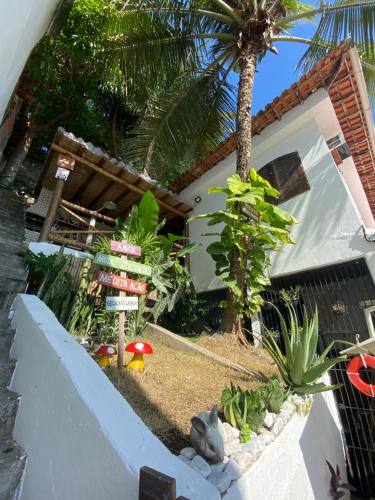 a garden in front of a house with a palm tree at Casa Vila Mar - Inn Prainha in Arraial do Cabo