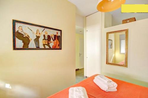 TLV Living Apartment في تل أبيب: غرفة نوم بسرير برتقالي ولوحة على الحائط