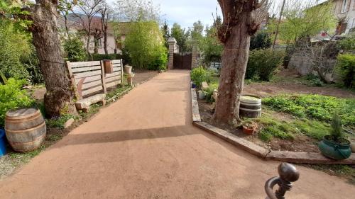 a walkway in a garden with trees and a fence at Le gîte du Tarn in Aguessac