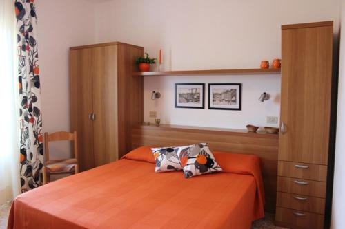 a bedroom with a bed with an orange bedspread at APPARTAMENTI ZUCCALE - A 200 mt dalla spiaggia in Capoliveri