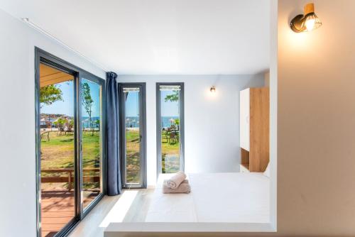 a bedroom with large windows and a bed with a view at Vilas in the garden by the sea in Sikia