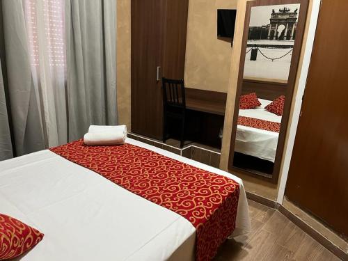 een slaapkamer met een spiegel en een bed met een rode deken bij Albergo Corvetto Corso Lodi in Milaan