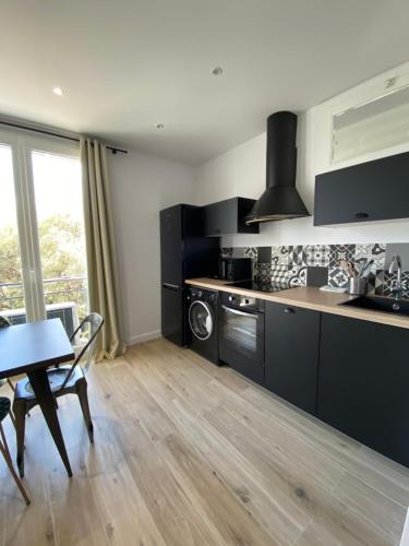 une cuisine avec des armoires noires et une table ainsi qu'une salle à manger dans l'établissement Ajaccio Magnifique T2 45m2 neuf 5 personnes Clim wifi stationnement gratuit centre ville plage à 300m, à Ajaccio