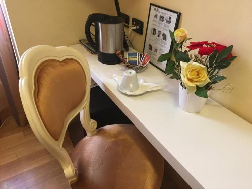 a desk with a vase of flowers and a chair at Locanda San Paolo in Monza