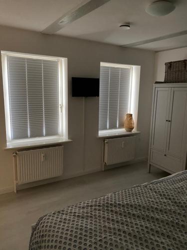 a bedroom with two windows and a bed and a television at Hafenkoje Husum in Husum