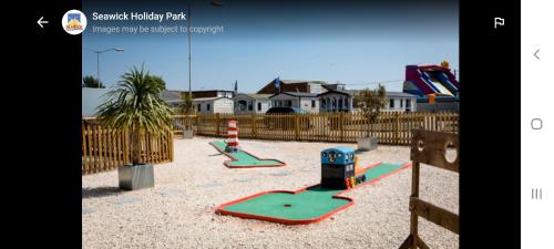 un parque infantil con 2 equipos de juego en la arena en Jacqueline's holiday homes seawick clacton on sea en Saint Osyth