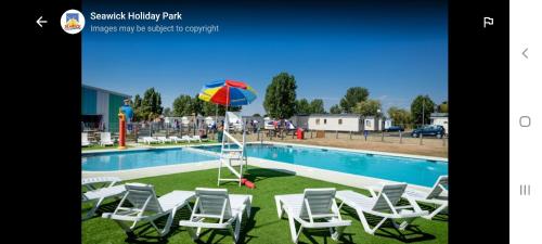 a group of chairs and an umbrella next to a swimming pool at Jacqueline's holiday homes seawick clacton on sea in Saint Osyth