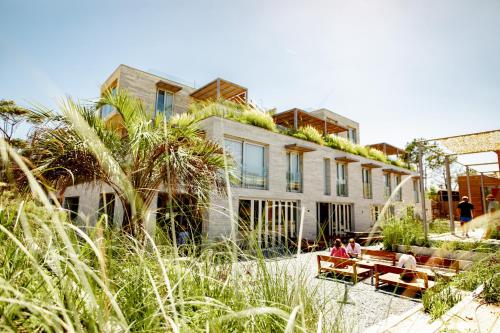 a building with people sitting on benches in front of it at Casagrande Hotel & Beach Club in José Ignacio