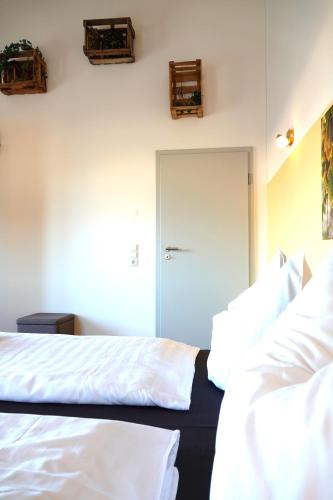 a bedroom with a bed with white sheets and a door at Weinbergshof Rickel in Kitzingen