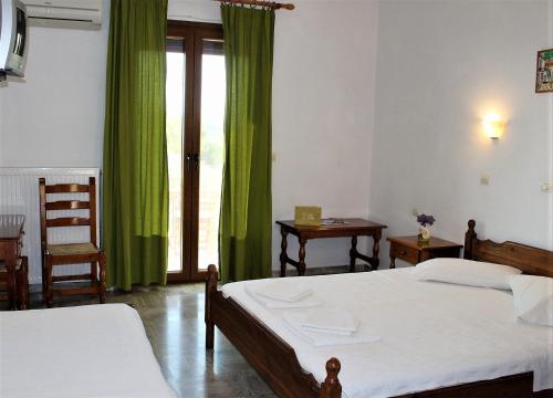 a bedroom with two beds and a window with green curtains at Molivos View Studios in Mithymna