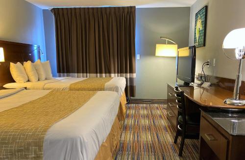 a hotel room with two beds and a flat screen tv at Travelodge by Wyndham Bloomington in Bloomington