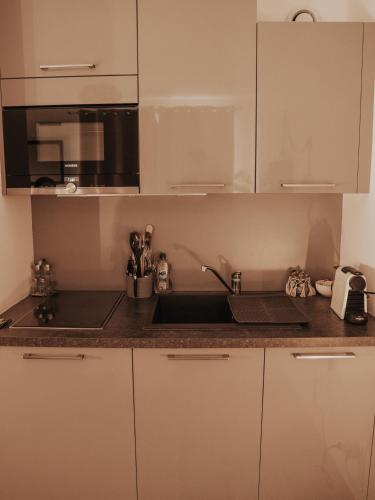 une cuisine avec des armoires blanches et un évier dans l'établissement Studio tt confort coeur ville avec terrasse et parking gratuit, à Sanary-sur-Mer