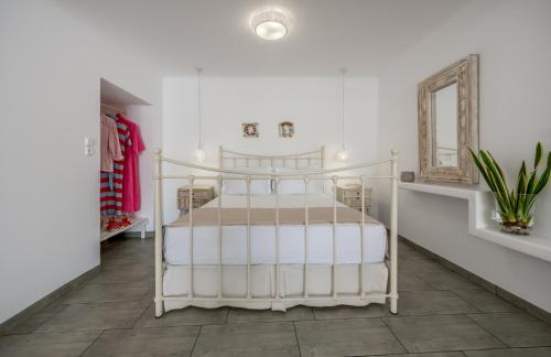 a white bed in a white room with a mirror at Achinos By The Sea Milos in Agia Irini Milos