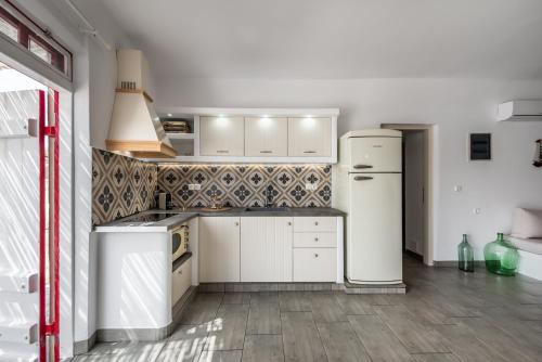 a kitchen with white cabinets and a refrigerator at Achinos By The Sea Milos in Agia Irini Milos