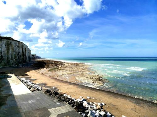 a beach with rocks and the ocean on a cloudy day at Appartement Cosy in Ault