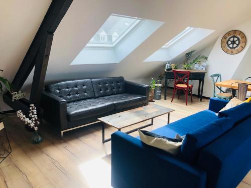 a living room with a black leather couch and a table at "LA FABRIQUE" en HYPERCENTRE PARKING GRATUIT in Amiens