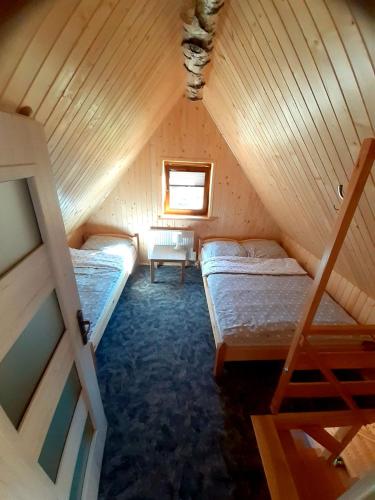 a attic room with two beds and a window at Domek na Leśnej in Łapsze Niżne