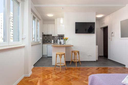 a kitchen with white walls and wooden floors and stools at Botan Apartment in Split
