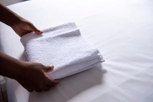 a person holding a stack of towels on a table at Ecomotel O.R.Tambo in Kempton Park
