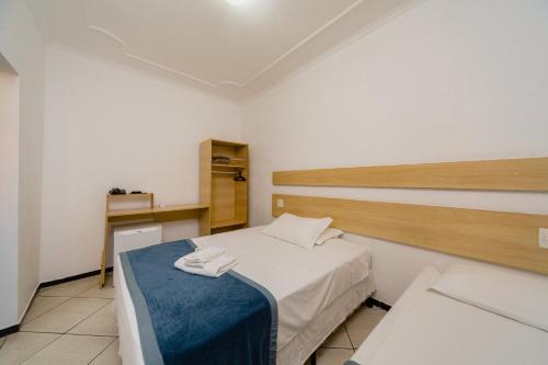a small room with a bed with a blue blanket at Hotel Jardim in Jaú