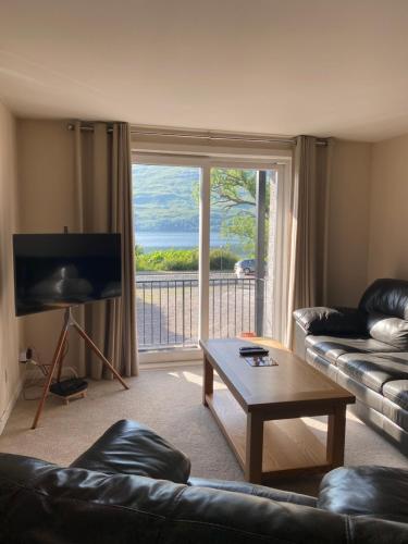 a living room with a couch and a table and a large window at Conaglen, one bedroom apartment with stunning views. in Fort William