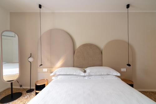 a bedroom with a large white bed and two mirrors at Palazzo Miracoli Apartments in Venice