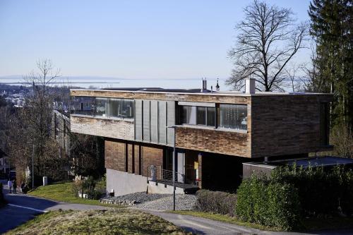 a brick house on a hill with a street at Design Apartment mit Naturblick in Bregenz