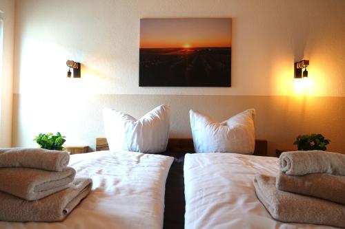 two beds in a hotel room with white sheets and pillows at Weinbergshof Rickel in Kitzingen
