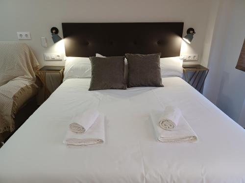 ein großes weißes Bett mit zwei Handtüchern darauf in der Unterkunft Apartamento Luxury Triana-Los Remedios in Sevilla