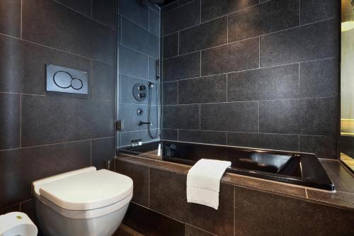 a bathroom with a toilet and a bath tub at U&Me; BW Signature Collection in Umeå