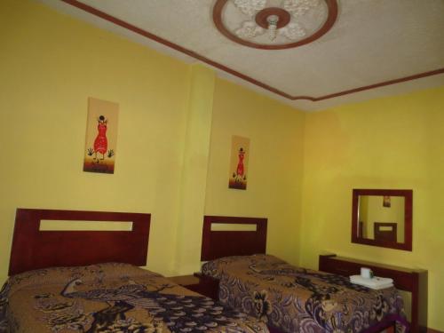 two beds in a room with yellow walls at Hotel Campo Real Plus Tamasopo in Tamasopo