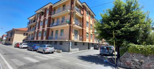 un edificio alto con coches estacionados frente a él en LE PALME Loft Apartment en Fossano