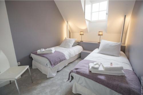 deux lits dans une petite pièce avec une fenêtre dans l'établissement Les Suites du Château de Cheverny, à Cheverny