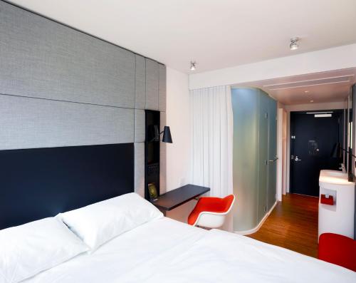 a bedroom with a bed and a red chair at citizenM Los Angeles Downtown in Los Angeles
