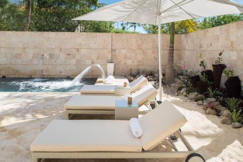 a group of lounge chairs and an umbrella next to a pool at Royalton Splash Punta Cana, An Autograph Collection All-Inclusive Resort & Casino in Punta Cana