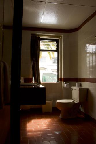 a bathroom with a toilet and a window at Hotel Ambassador in Quito