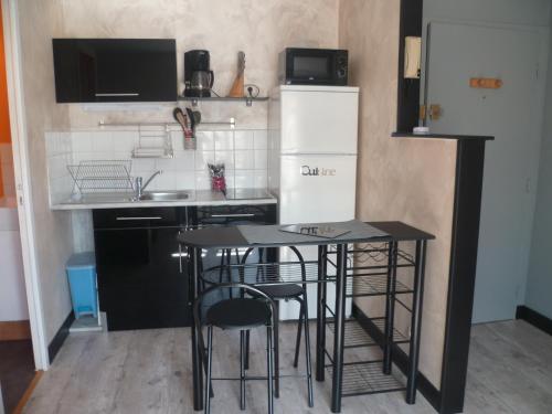 - une cuisine avec deux tables noires et un réfrigérateur dans l'établissement studio, au Mans