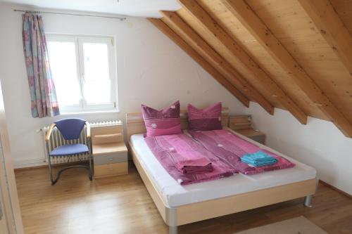 Un dormitorio con una cama con sábanas rosas y una silla. en Bodensee Loge, en Radolfzell am Bodensee